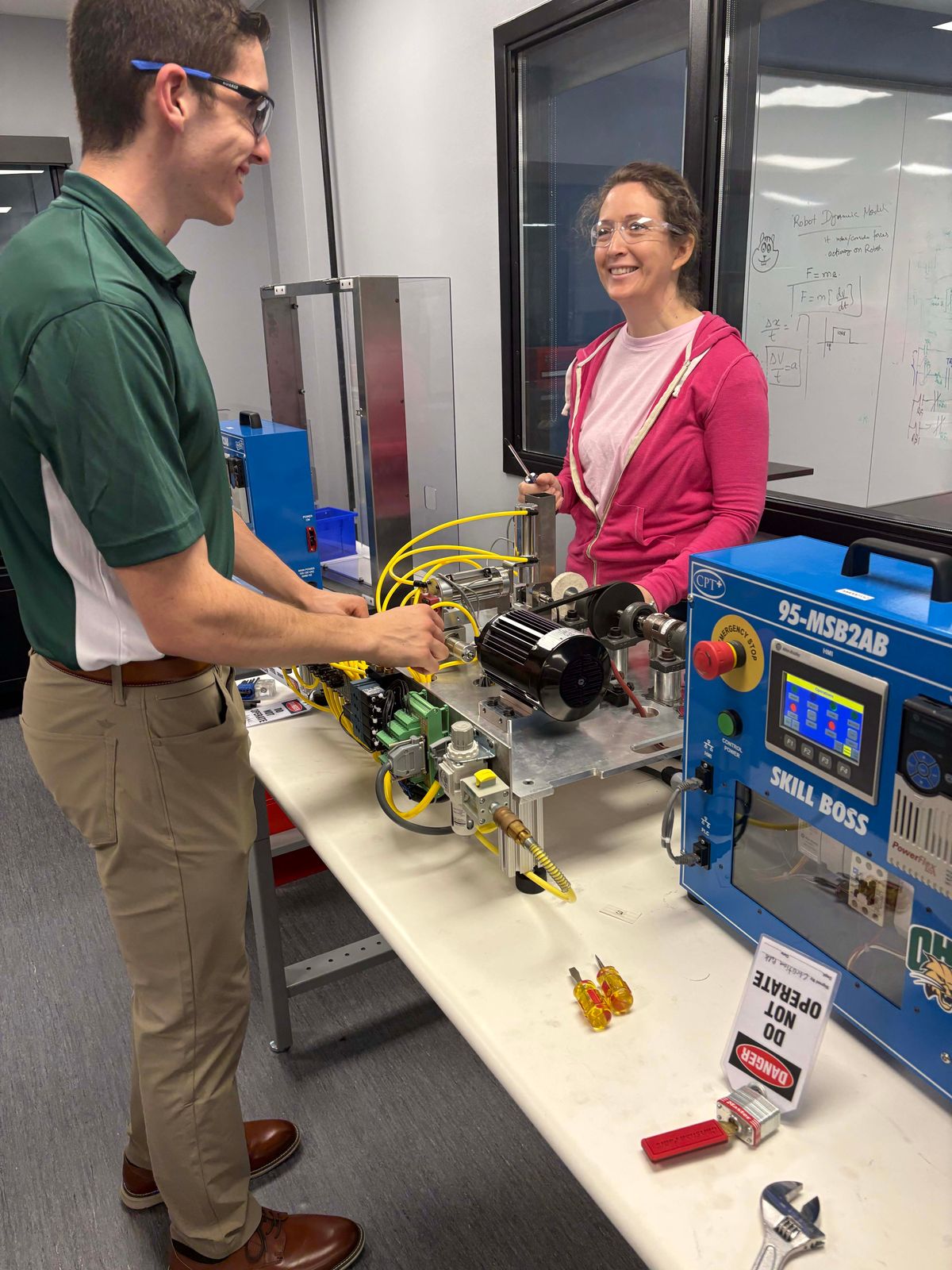 Adult students working on an industrial trainer with an instructor.