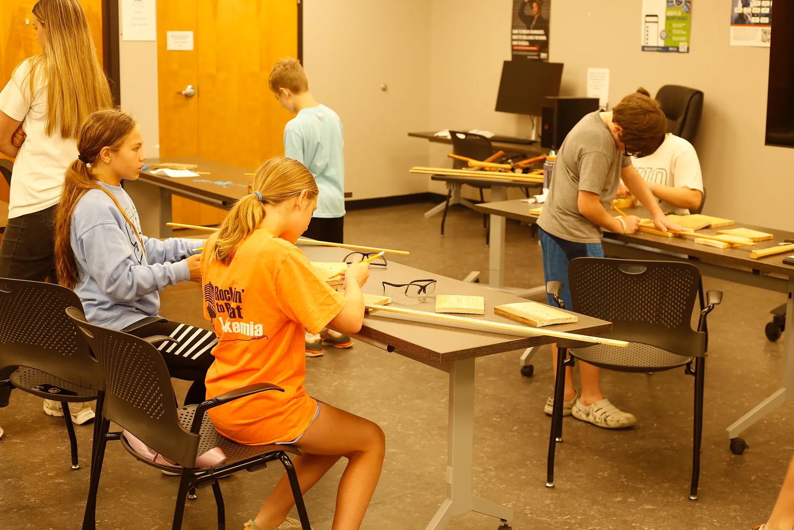 Students measuring and cutting wood at an EXPLORE summer career camp.