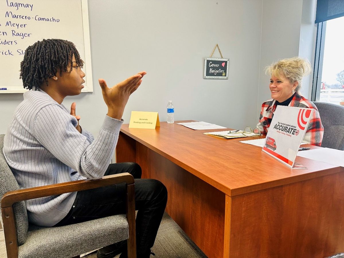 A student practicing a mock interview with an employer at the Career Navigators table.