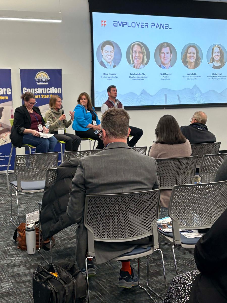 An employer panel presenting to a seated audience in a Workforce Center meeting room.