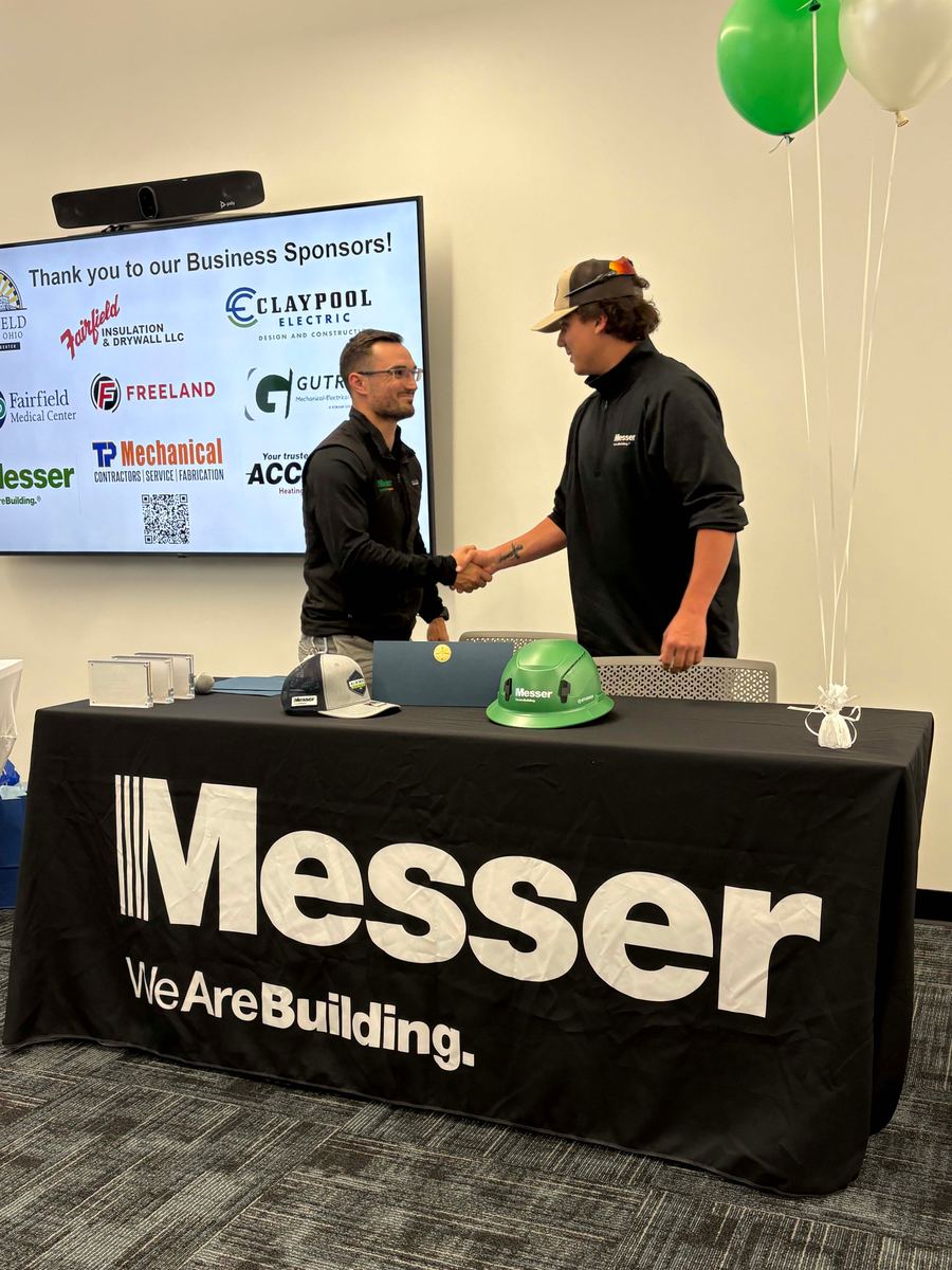 A student shaking hands with an employer partner at a signing event.